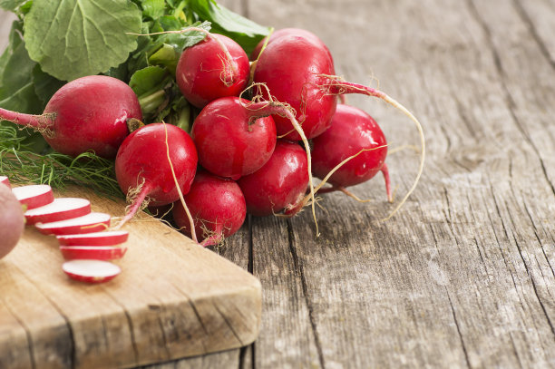 取一捆新鲜生红萝卜，放在切好的萝卜片上。健康有机蔬菜(萝卜)图片下载