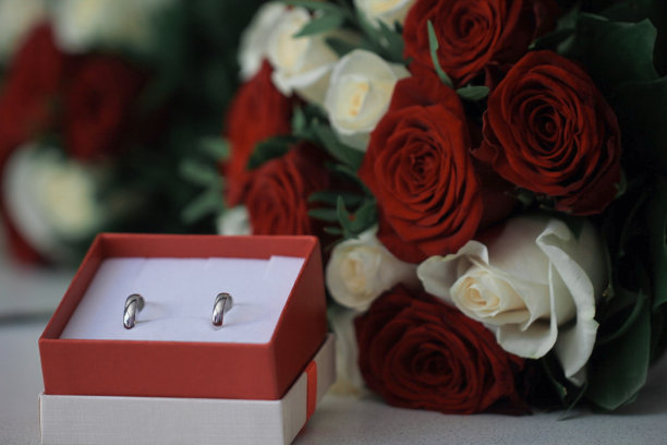 一个近距离的结婚戒指在盒子里与红和白玫瑰图片下载