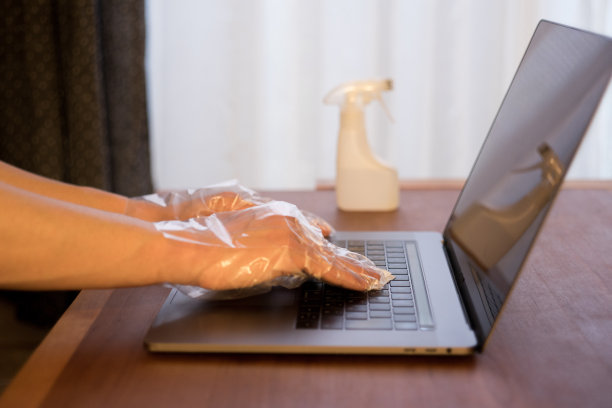 用乙醇消毒剂擦拭笔记本电脑表面细菌和病毒的特写照片图片下载