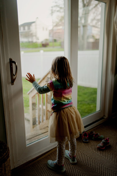 小女孩站在滑块门，从一个黑暗的房子看外面图片下载