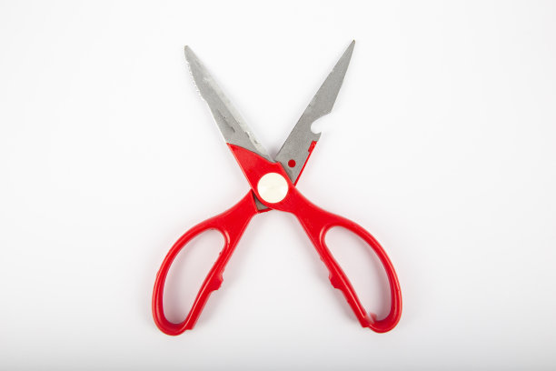 红色塑料手柄的剪刀，白色背景。图片下载
