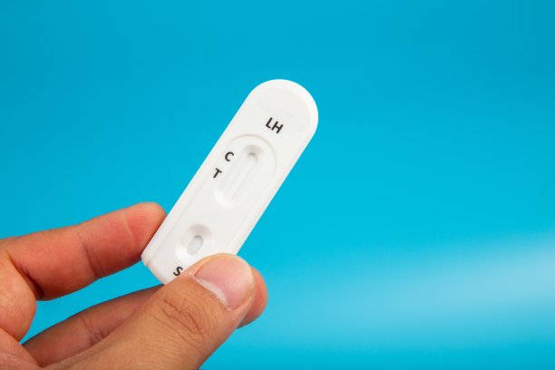 男子手拿着怀孕检测试剂盒，蓝色背景。图片下载