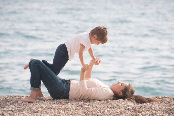 年轻的母亲和可爱的孩子在春天的海滩上玩休闲运动图片下载
