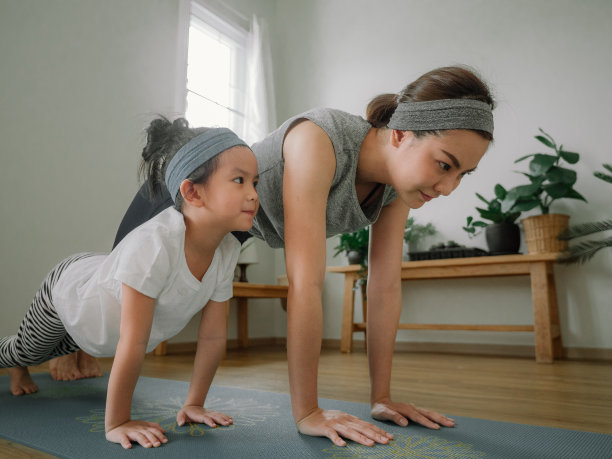 年轻的母亲和女儿在家里做练习。图片下载