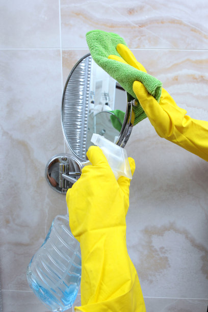 手戴黄色橡胶手套擦拭浴室的圆镜。无法分辨的照片。清洁和清洁的概念。图片下载