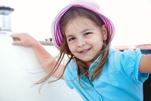 可爱的小女孩在船上旅行，享受着平静的大海，用快乐的表情看着镜头图片下载