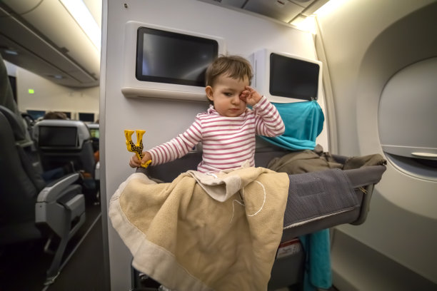 昏昏欲睡的小可爱坐在飞机的摇篮里用玩具揉眼睛。特写,软焦点图片下载