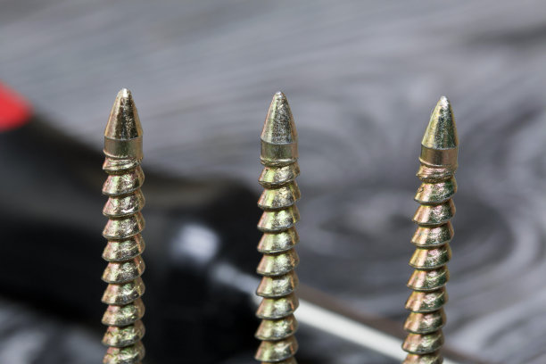 几个黄色的金属螺丝和一个螺丝刀。他们躺在涂成黑色的松木刷板上。世界劳动节。图片下载