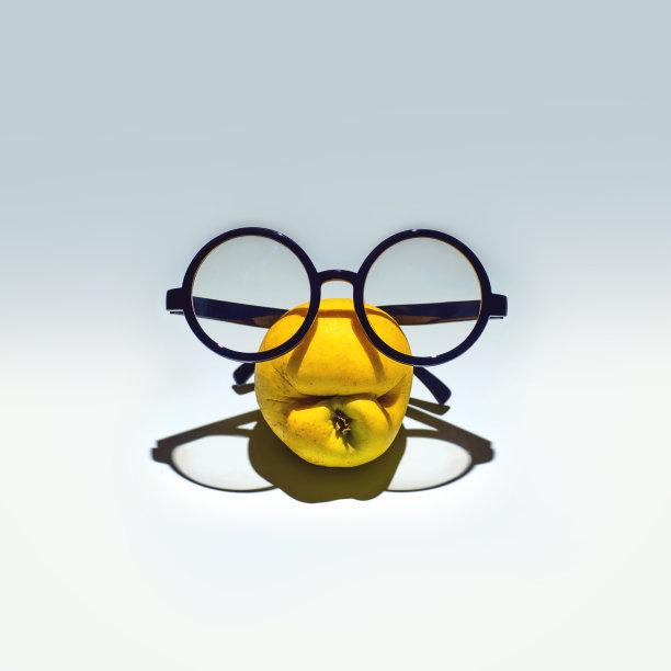 又黄又皱的苹果，戴着眼镜做鬼脸。在浅蓝色的背景上图片下载