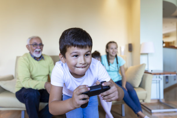 一个快乐的小女孩和她的弟弟在客厅里玩电脑游戏。图片下载