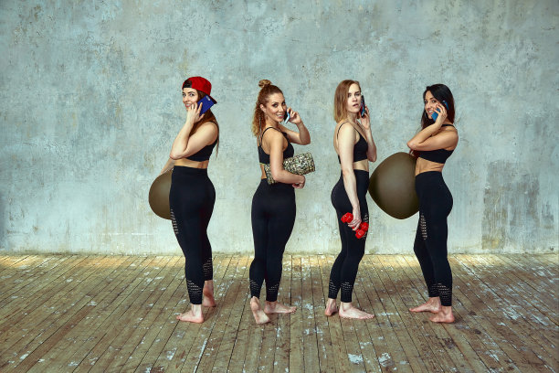 一群运动女性朋友在手机上使用这款应用程序，看智能手机屏幕，发短信，看照片，在锻炼后放松，在健身房锻炼间隙图片下载