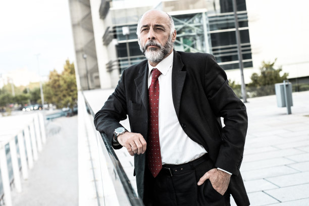 深思熟虑的商人站在屋顶上望着远方图片下载