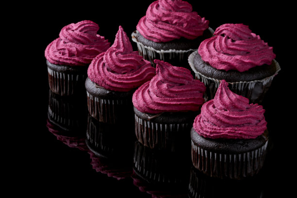 素食巧克力和黑醋栗纸杯蛋糕。上面有腰果和黑醋栗奶油的黑松饼。黑色镜面背景与反射图片下载