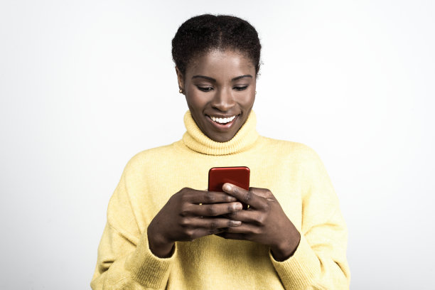 微笑的非裔美国女人用智能手机发短信图片下载