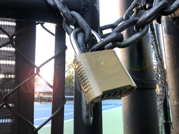 网球场大门上的金属挂锁的特写照片，设施对公众关闭图片下载