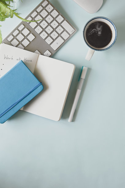 俯视图舒适的工作空间。电脑笔记本，热咖啡杯，马克笔，笔记本，日记本，玻璃花瓶中的鲜花平铺在办公桌上。图片下载