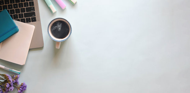 俯视图舒适的工作空间。电脑笔记本，热咖啡杯，马克笔，笔记本，日记本，玻璃花瓶中的鲜花平铺在办公桌上。图片下载
