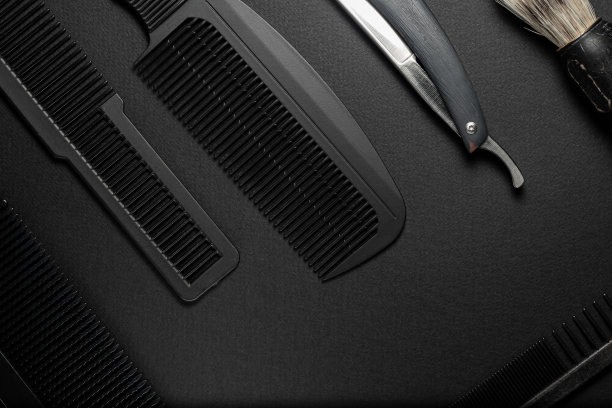 黑色的表面上是旧的理发师工具。梳子，剃须刀，剃须刷。黑色的单色。水平方向。lat雷。图片下载
