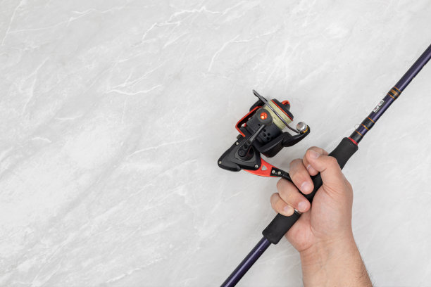 男性的手与鱼竿和钓鱼卷轴与复制空间上方的白色背景。图片下载