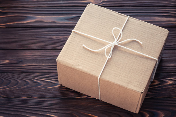 用线绑在深色木板上的棕色硬纸盒。包裹递送服务理念。图片下载