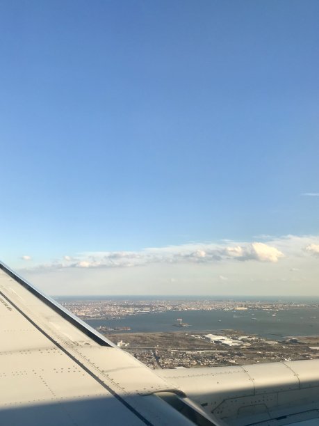 从飞机机翼窗口拍摄的国际旅行航拍照片:曼哈顿的天际线，美国著名的大都市，其高耸的摩天大楼为背景图片下载