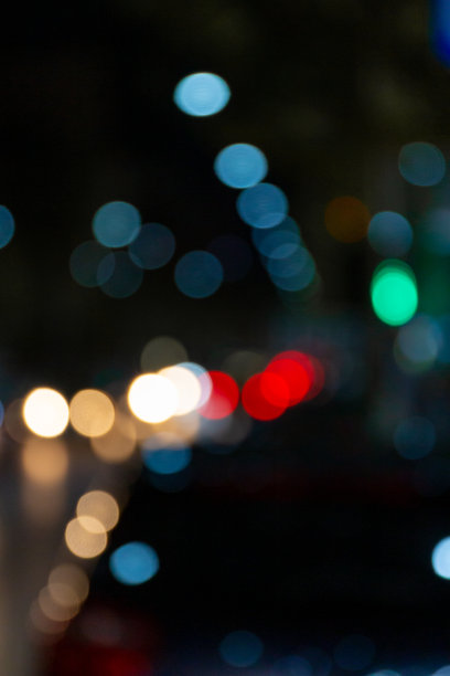 在不同颜色的灯光背景下的夜晚一条街的散景图片下载