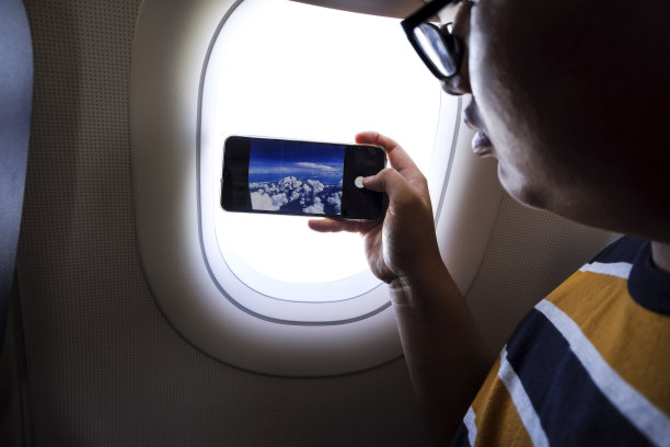 年轻乘客在商业飞机上使用智能手机图片下载