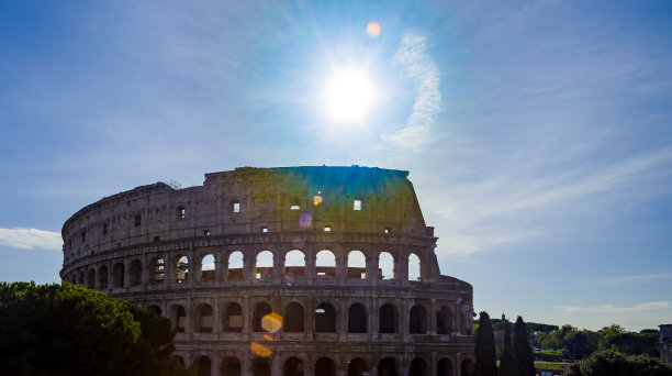 罗马斗牛场(斗牛场)剪影在蓝色的天空背景与灿烂的太阳和镜头光晕在罗马，意大利图片下载