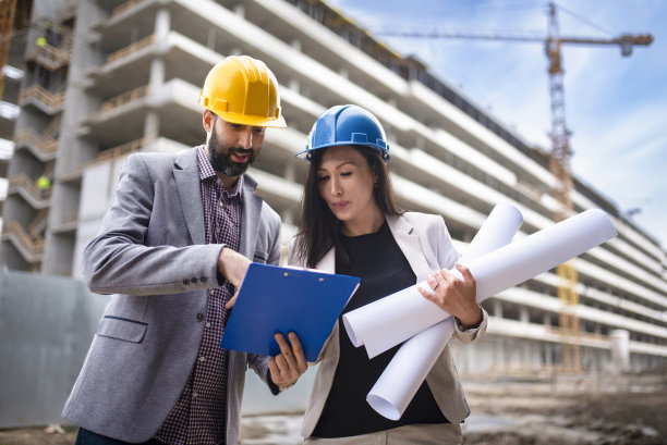 多民族工程师工人与图纸在建筑工地库存照片图片下载