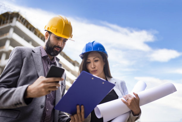 多民族工程师工人与图纸在建筑工地库存照片图片下载