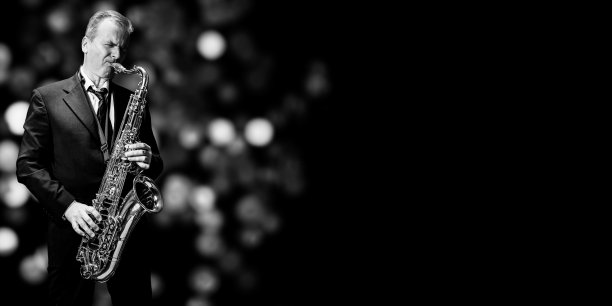 萨克斯管演奏者被隔离在黑色背景的左边(黑白)图片下载