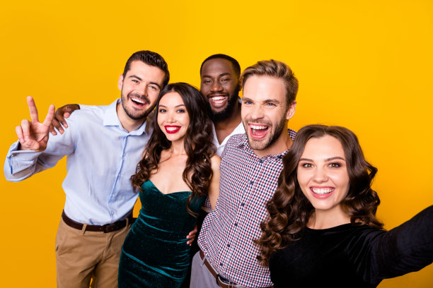 有吸引力的照片，两个漂亮的女士，三个大男子公司学生毕业派对最好的朋友哥们自拍显示v符号符号孤立的黄色背景图片下载