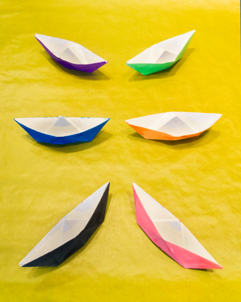 五颜六色的纸船在黄色的水面上对称排列图片下载