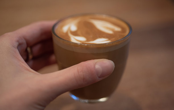 女士手捧一杯玛奇朵咖啡。图片下载