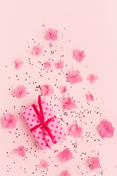 礼盒金色的五彩纸屑和鲜花在粉红色的节日拷贝空间。图片下载