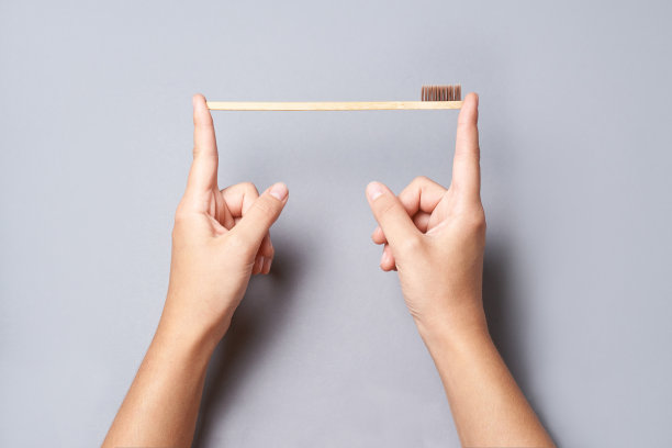 手握竹制生态牙刷。灰色背景图片下载