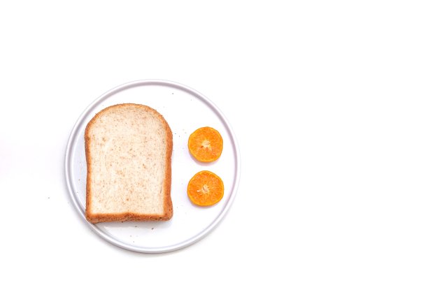 一片切成薄片的全麦面包和切了一半的橙子放在一个白色的盘子里图片下载
