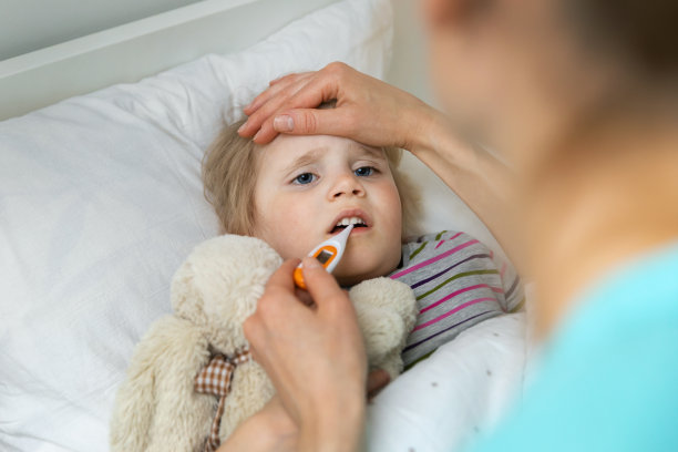 母亲躺在家里的床上安慰生病的孩子并测量体温图片下载