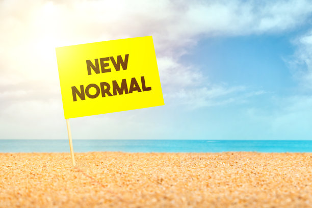 新冠肺炎后的新常态。一张写着“新常态”的卡片放在沙滩上。图片下载