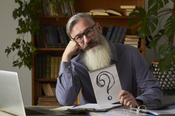 远程教育的概念。教师、翻译、家教在图书馆的桌面上带着疑问牌看着相机，选择性对焦图片下载