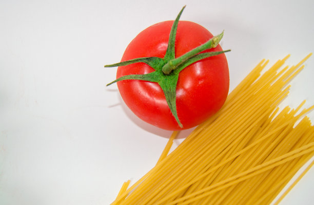 烹饪传统意大利面的原料——生意大利面和番茄，俯视图，白色背景，空间拷贝图片下载