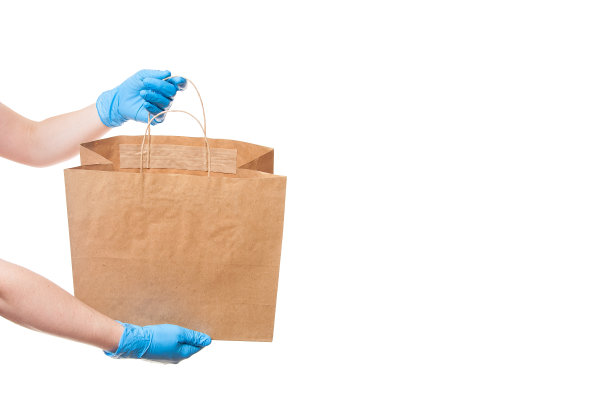 手在无菌手套的信使为安全交付的货物在一个环保的包装显示一个未标签的包装没有标志孤立在一个白色的背景与复制空间。图片下载