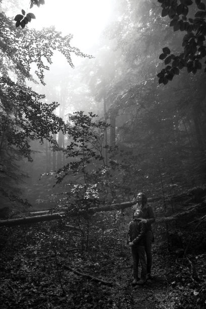 母亲和儿子在神秘的绿色雾林。他们仰望着等待奇迹的发生图片下载