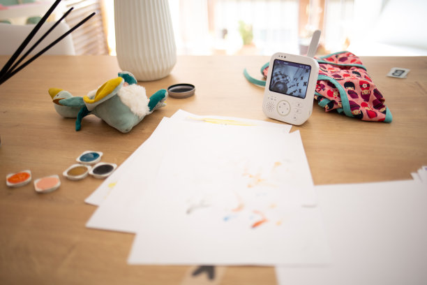 家庭作业有绘画、绘画、玩具和安全摄像头，供婴儿在木桌上工作图片下载
