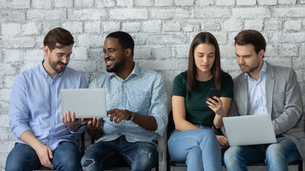 专注的不同的人在排队时使用笔记本电脑图片下载