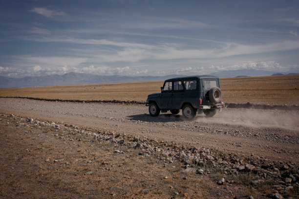 军车行驶在草原的碎石路上图片下载