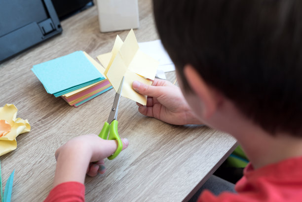 男孩正在给妈妈做纸花。母亲节，DIY检疫或在线教育理念。软焦点图片下载