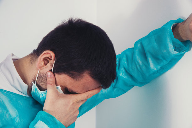 忧心忡忡的医生靠在墙上。图片下载