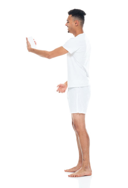 非裔美国青年男性穿着内衣站在白色背景前用手机拍照图片下载