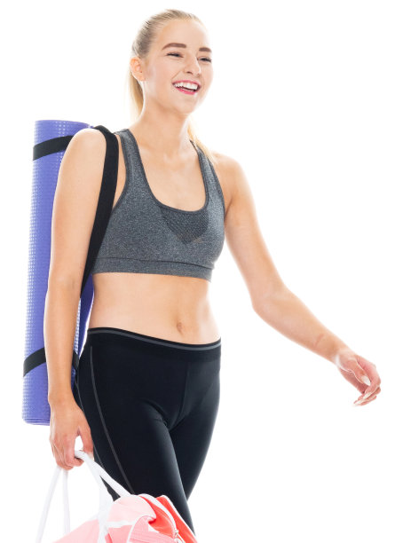 白种人年轻女性穿着瑜伽裤，拿着瑜伽包和运动垫在白色背景前准备做瑜伽图片下载